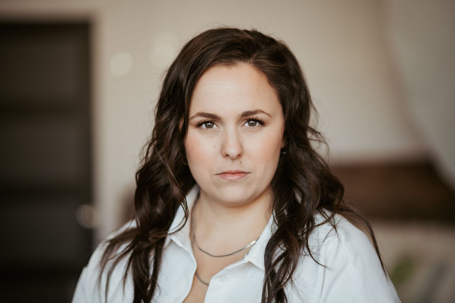 Professional portrait in white shirt against neutral background.