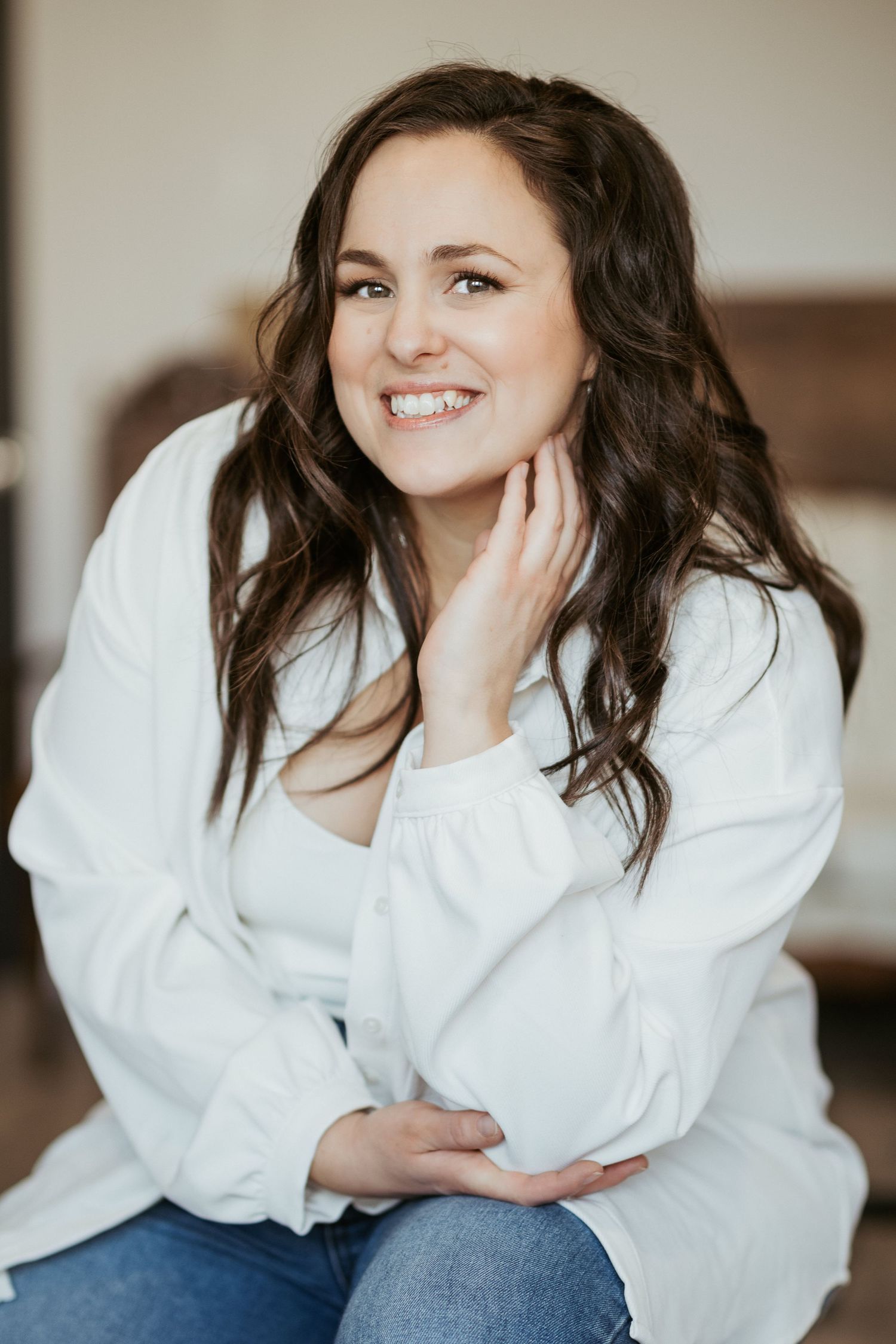 Portrait of person in white shirt and jeans against neutral background.