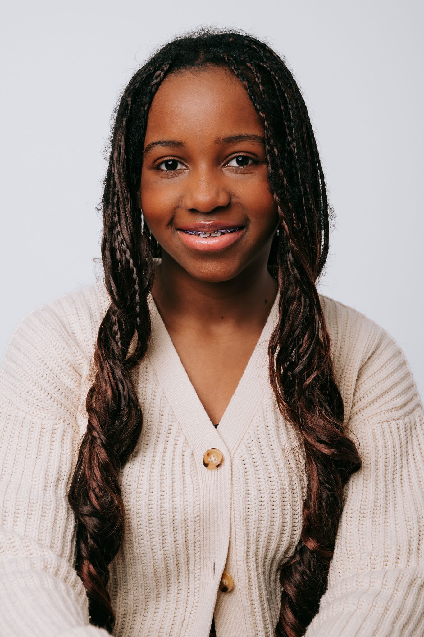 A person wearing a cream-colored knit sweater smiles warmly against a light background.