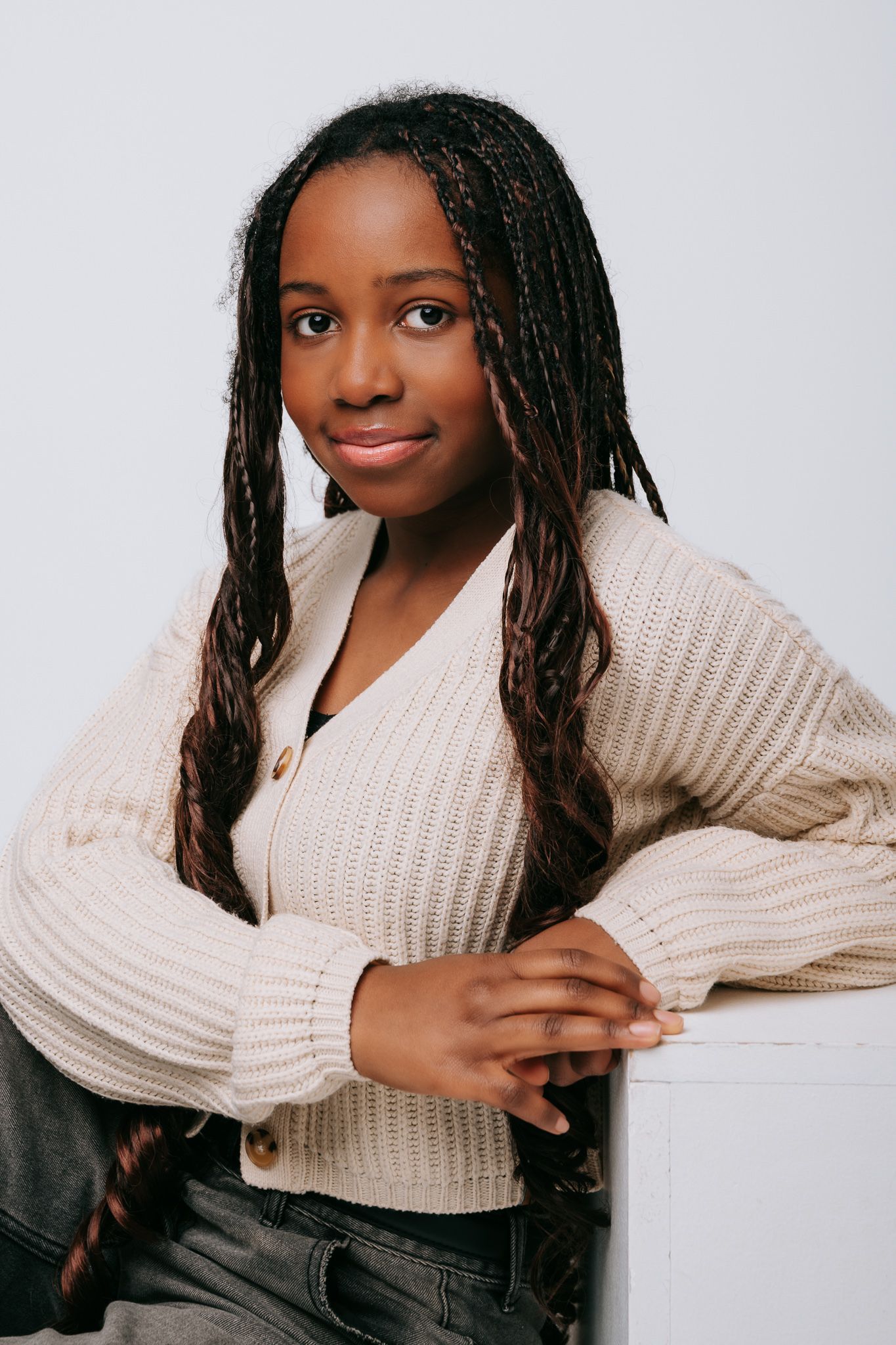 A series of four headshots showing a person in a cream knit sweater posing against a white background.