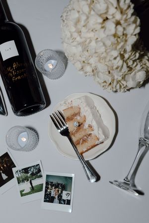 Wedding reception table setting with wine bottles, white hydrangeas, and vintage photographs on display.