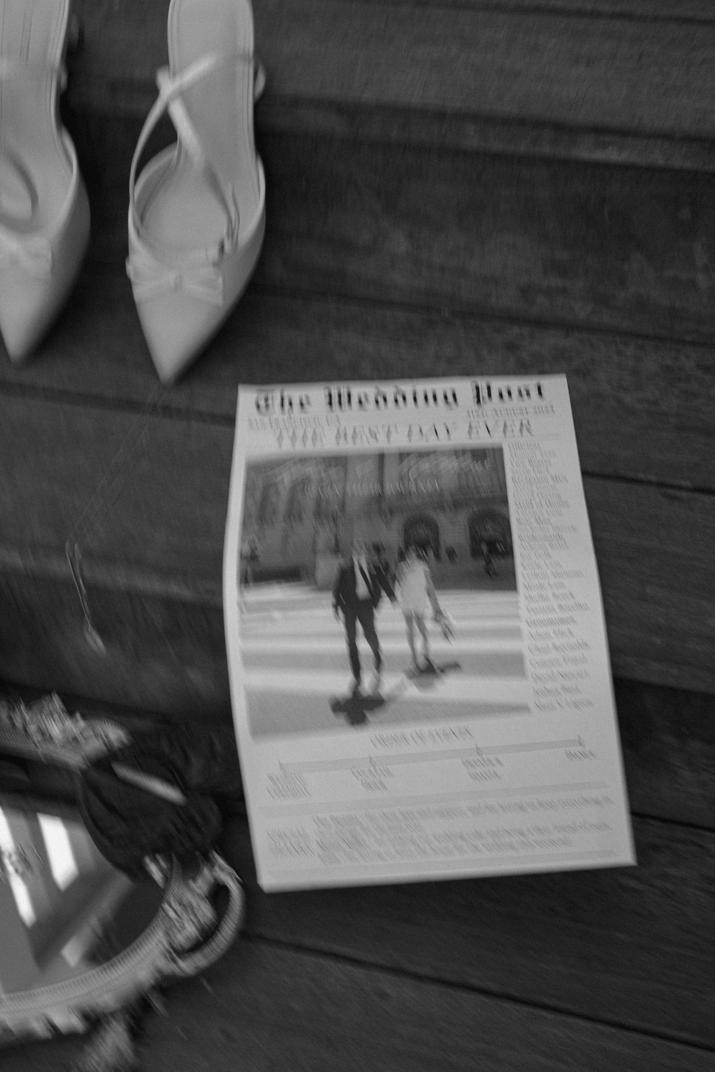 Black and white newspaper clippings and wedding items displayed on dark wooden stairs.