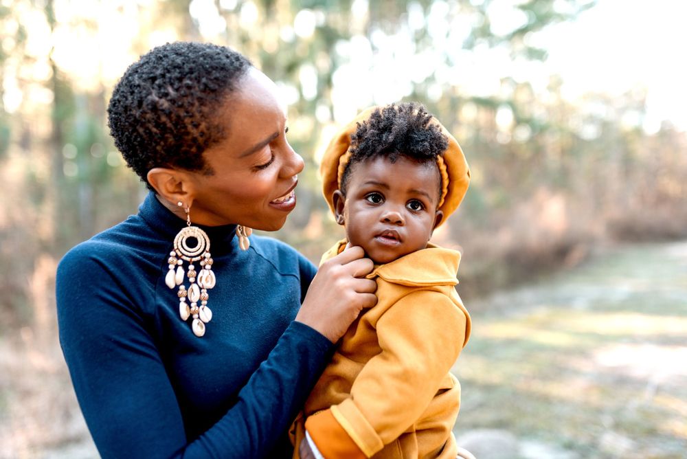 Parent and child sharing a tender moment outdoors in autumn wearing yellow and navy outfits.