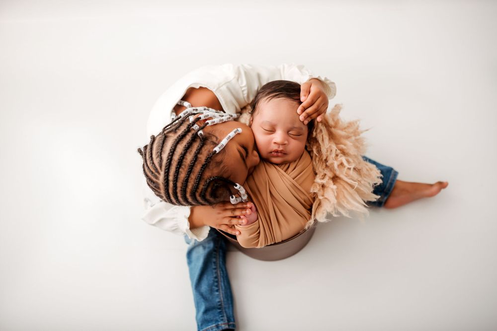 Newborn baby sleeping peacefully in brown outfit on white background.