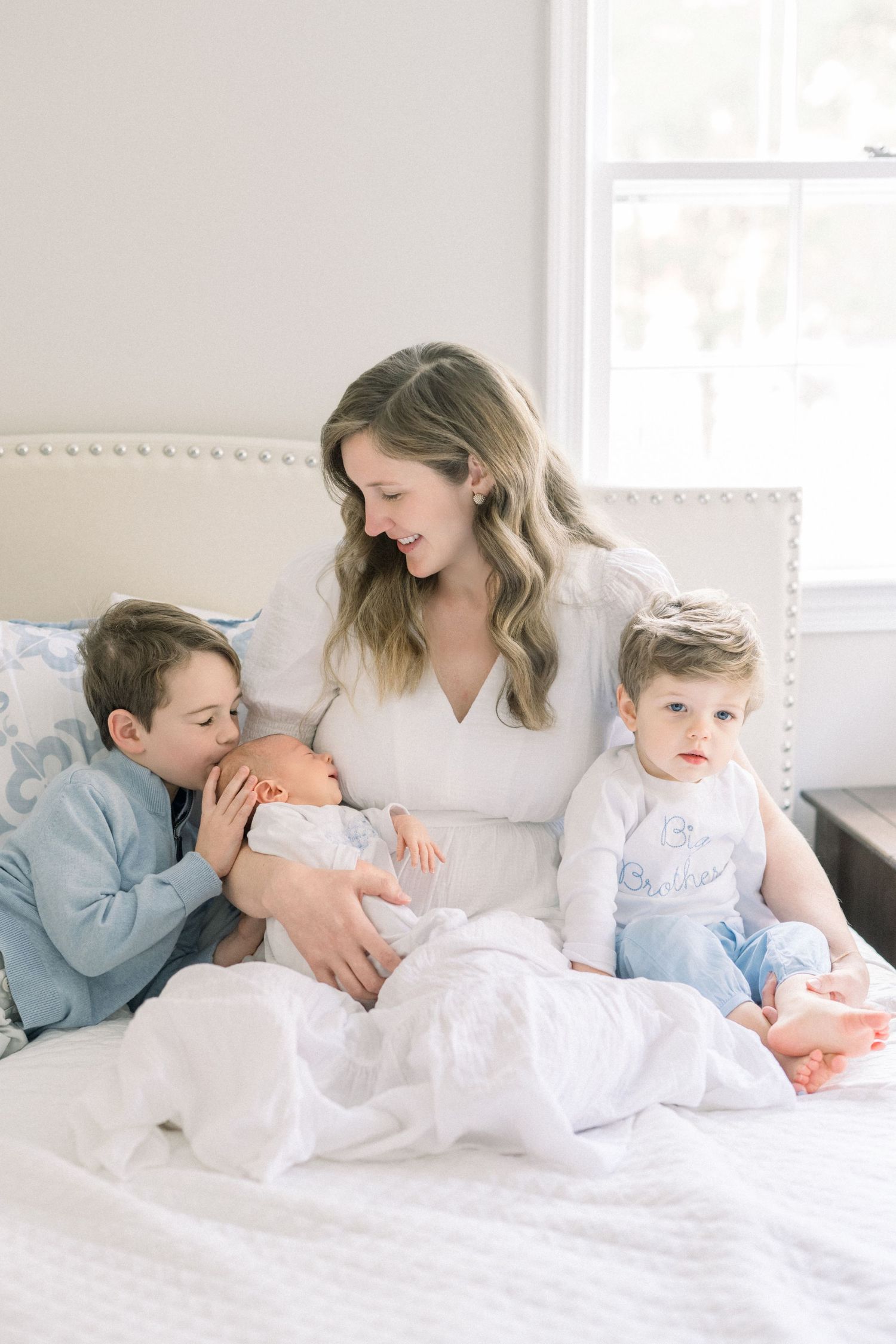 mom snuggling kids on bed with a newborn taken by a Washington DC Newborn Photographer