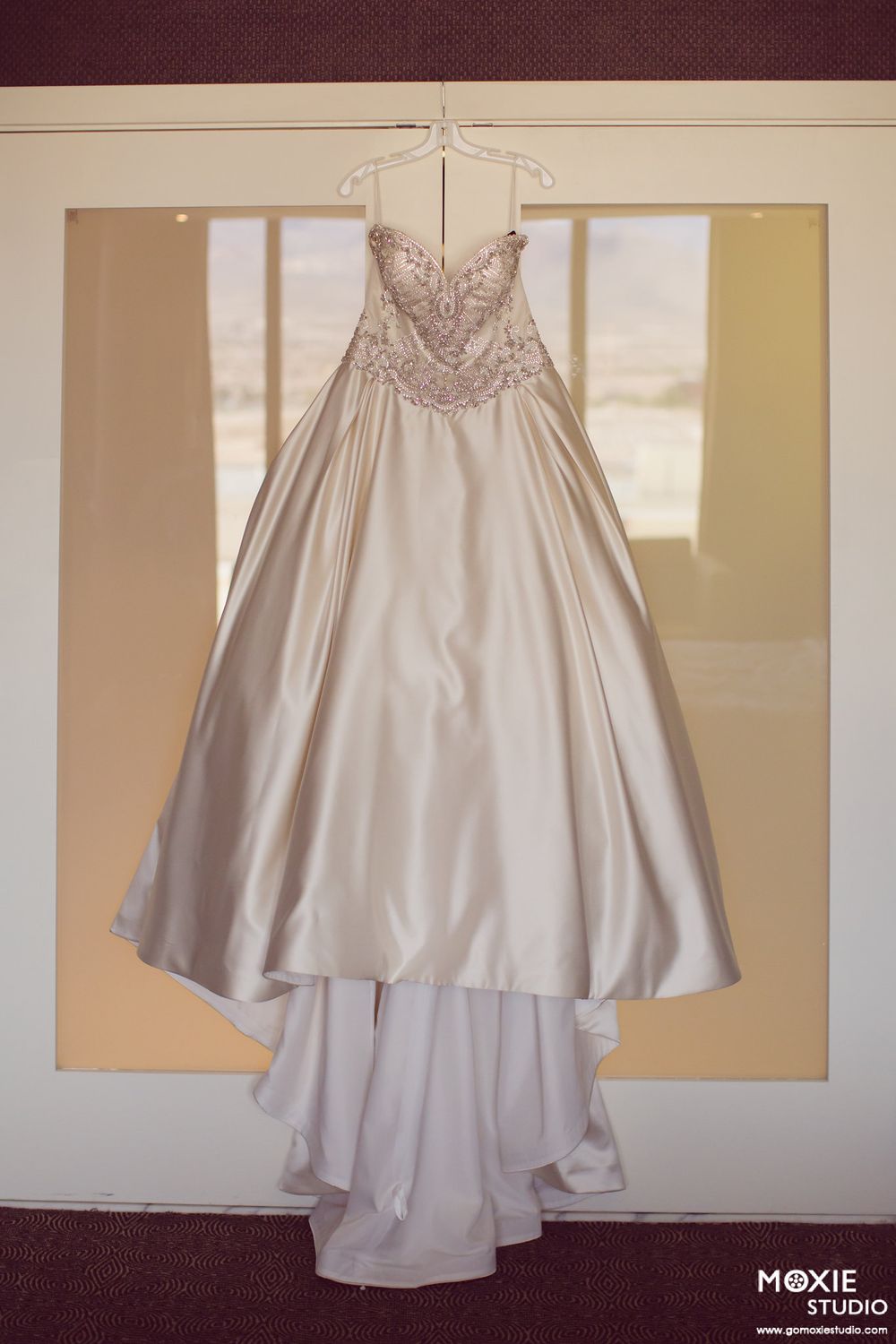 A sequence of photos showing a silver satin wedding dress displayed from different angles in a bridal studio.