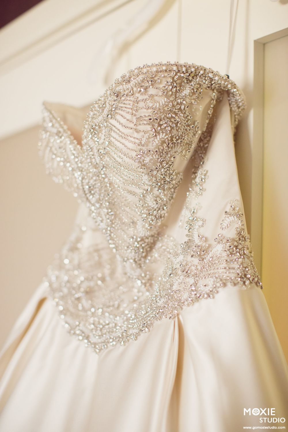 Close-up detail of a white wedding dress bodice with intricate crystal beading and embellishments.