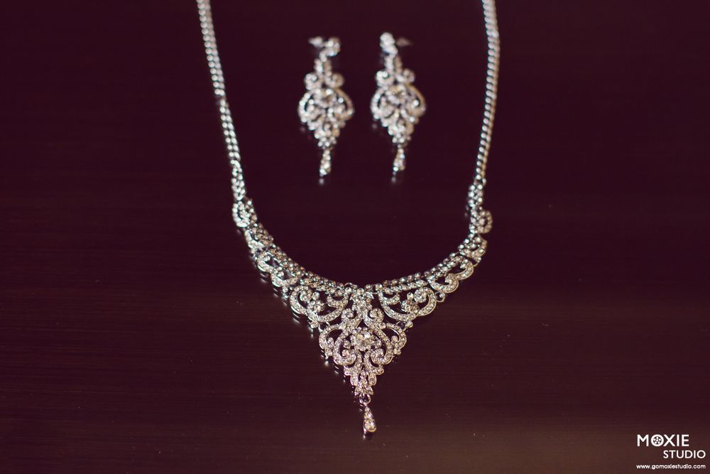 Elegant silver and crystal bridal jewelry collection featuring necklaces and earrings displayed on dark background.