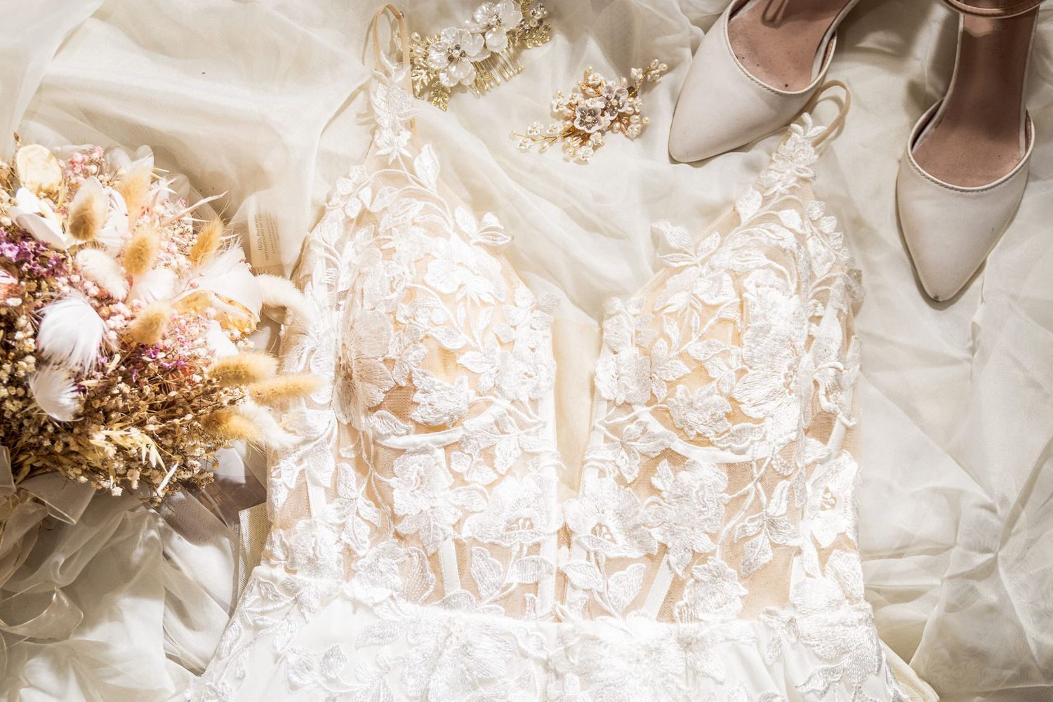 Escote de vestido de novia de encaje blanco con detalles de cuentas y flores decorativas.