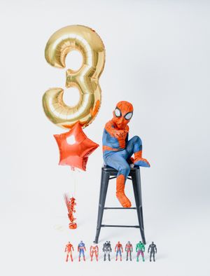 Spider-Man themed birthday setup with gold number 3 balloon and action figures.