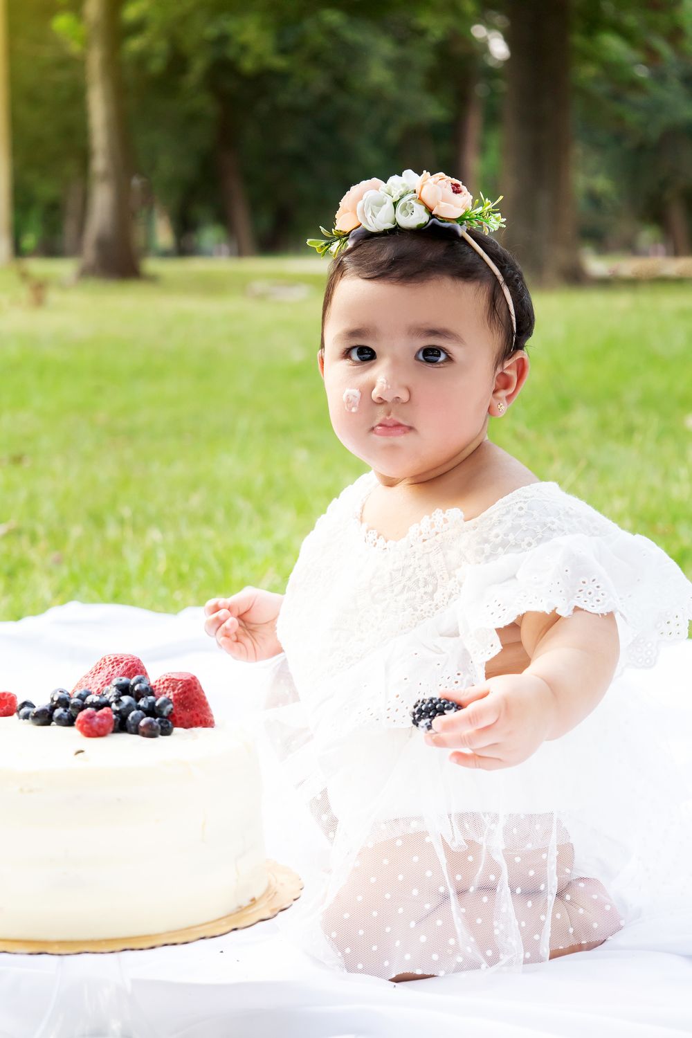 Outdoor picnic scene with fresh berries and white cake.
