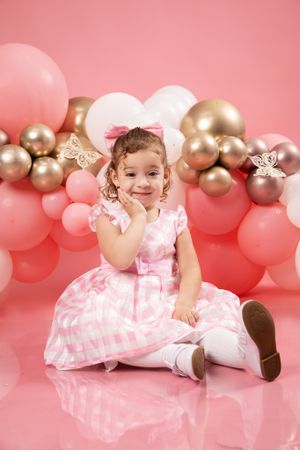 Festive birthday setup with pink and gold balloons against pink backdrop.