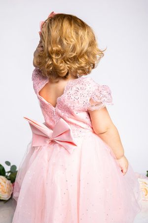 Back view of pink party dress with bow detail and lace sleeves.