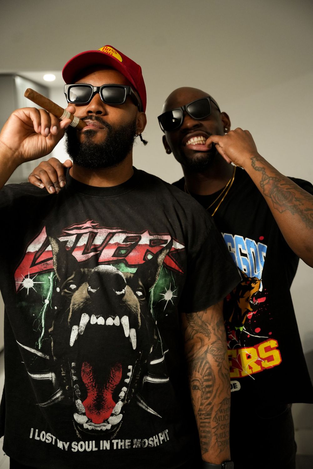 People wearing graphic t-shirts and caps posing together against a neutral background.