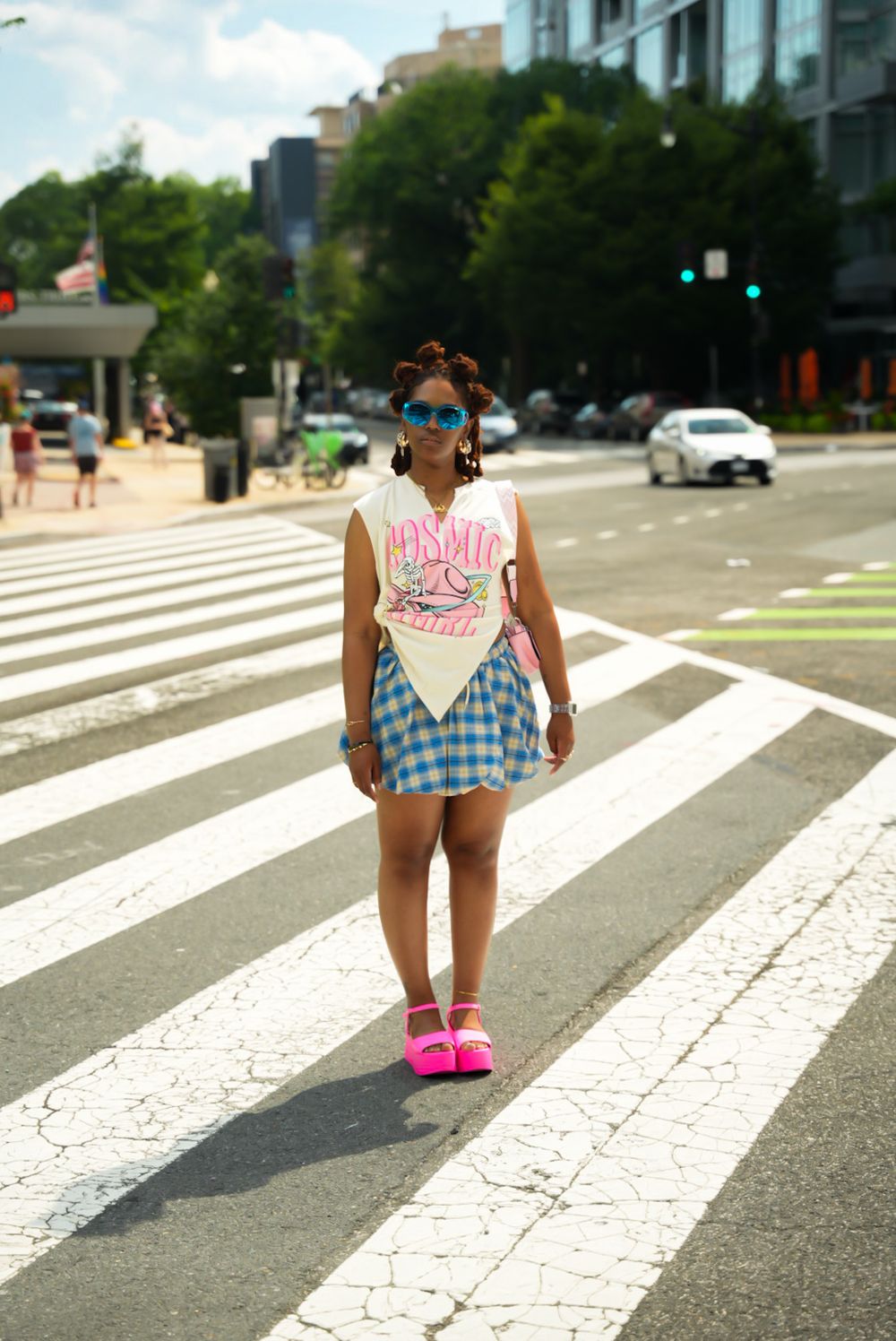 A sequence of photos showing someone walking across a crosswalk in a pink dress and blue checkered top on a sunny day.