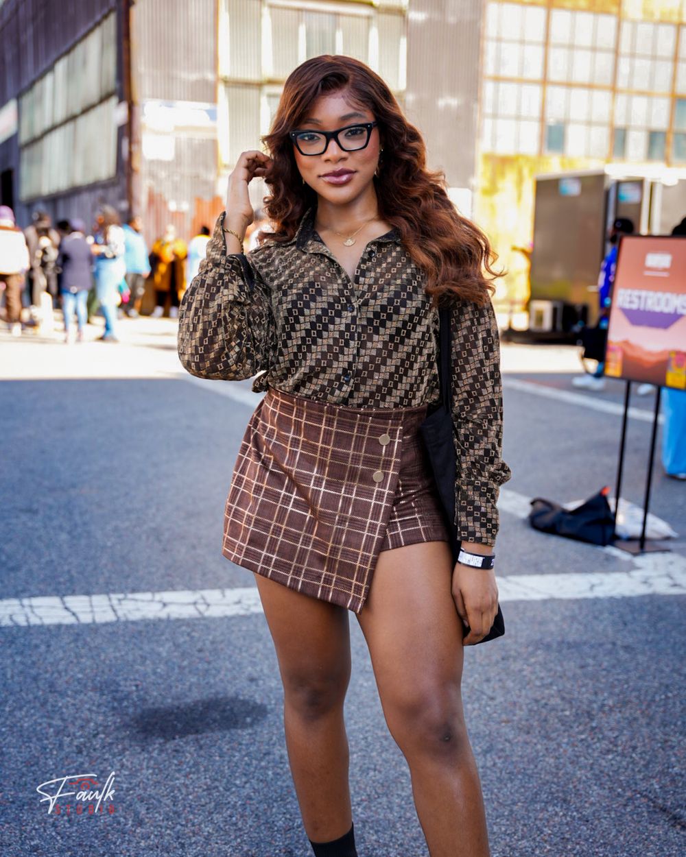 A person wearing a patterned top and shorts poses on a city street with buildings in the background.