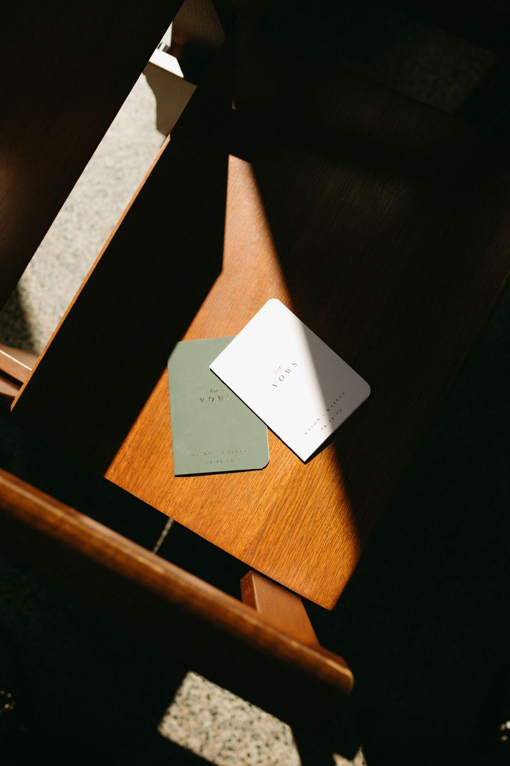 Wedding cards or invitations placed on a wooden surface in moody lighting.