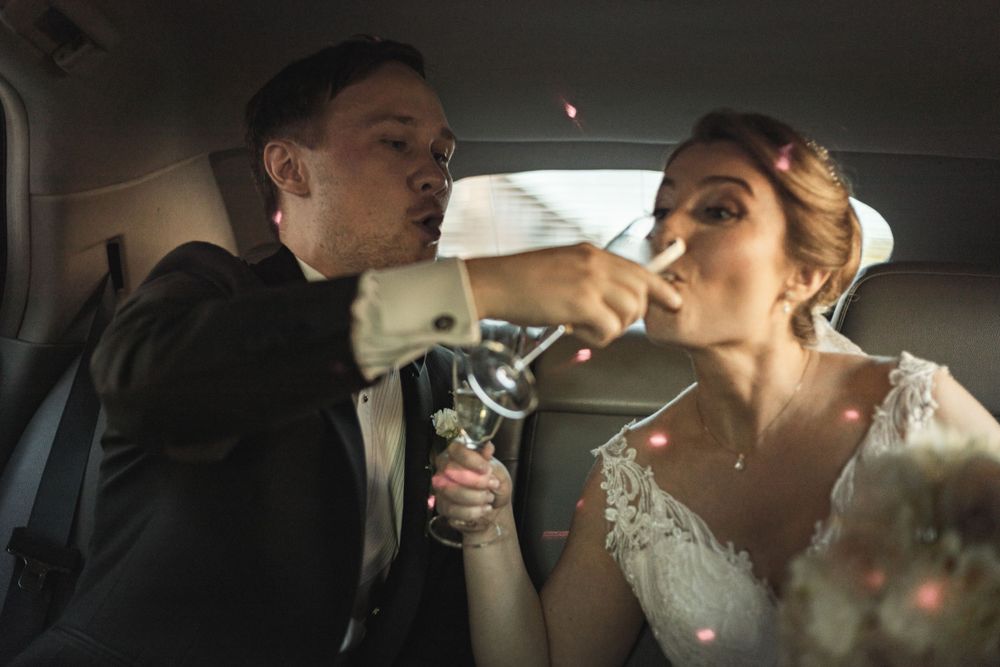 Brudpar skålar med champagne i bil under bröllopsdag i festlig stämning