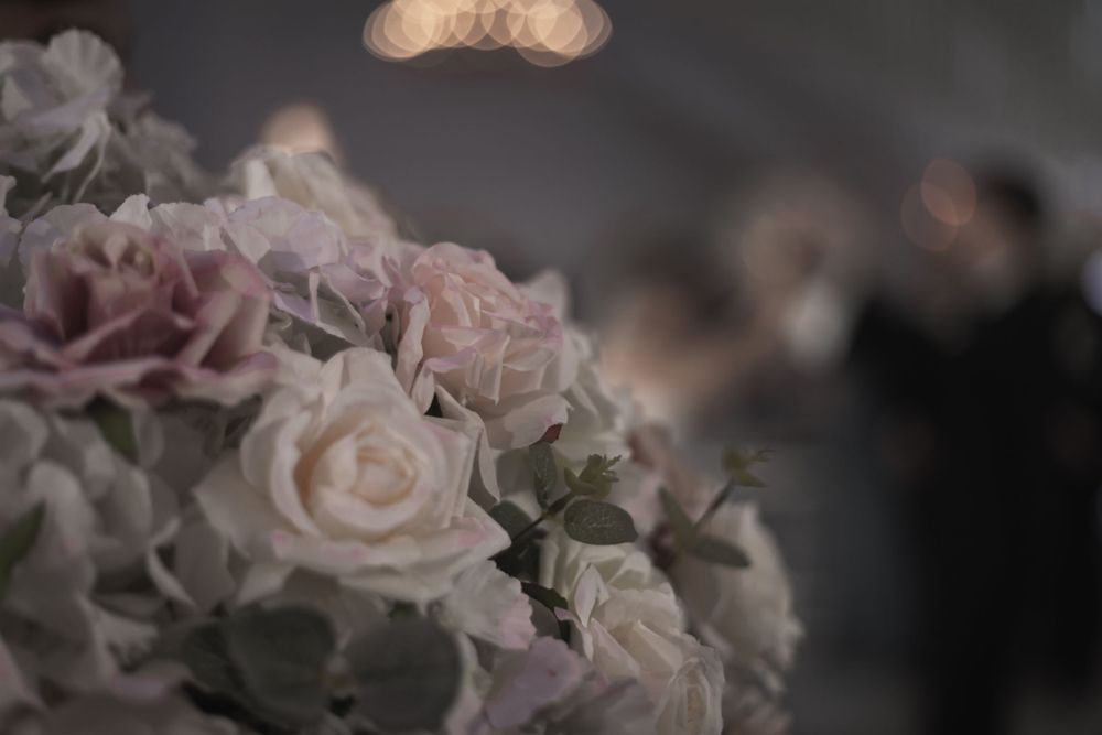 Bröllopsgäster i smoking skålar med champagne i elegant miljö ur fokus, blommor i förgrunden