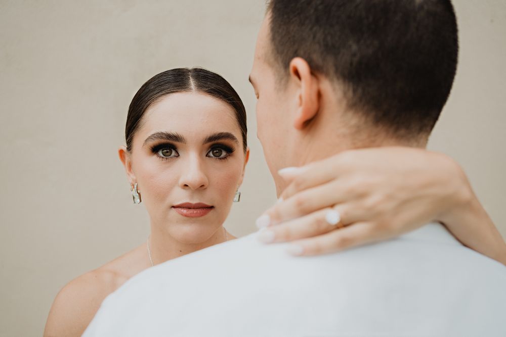 Bride’s serious expression as she gazes into the camera, with her partner’s back to the lens, creating contrast