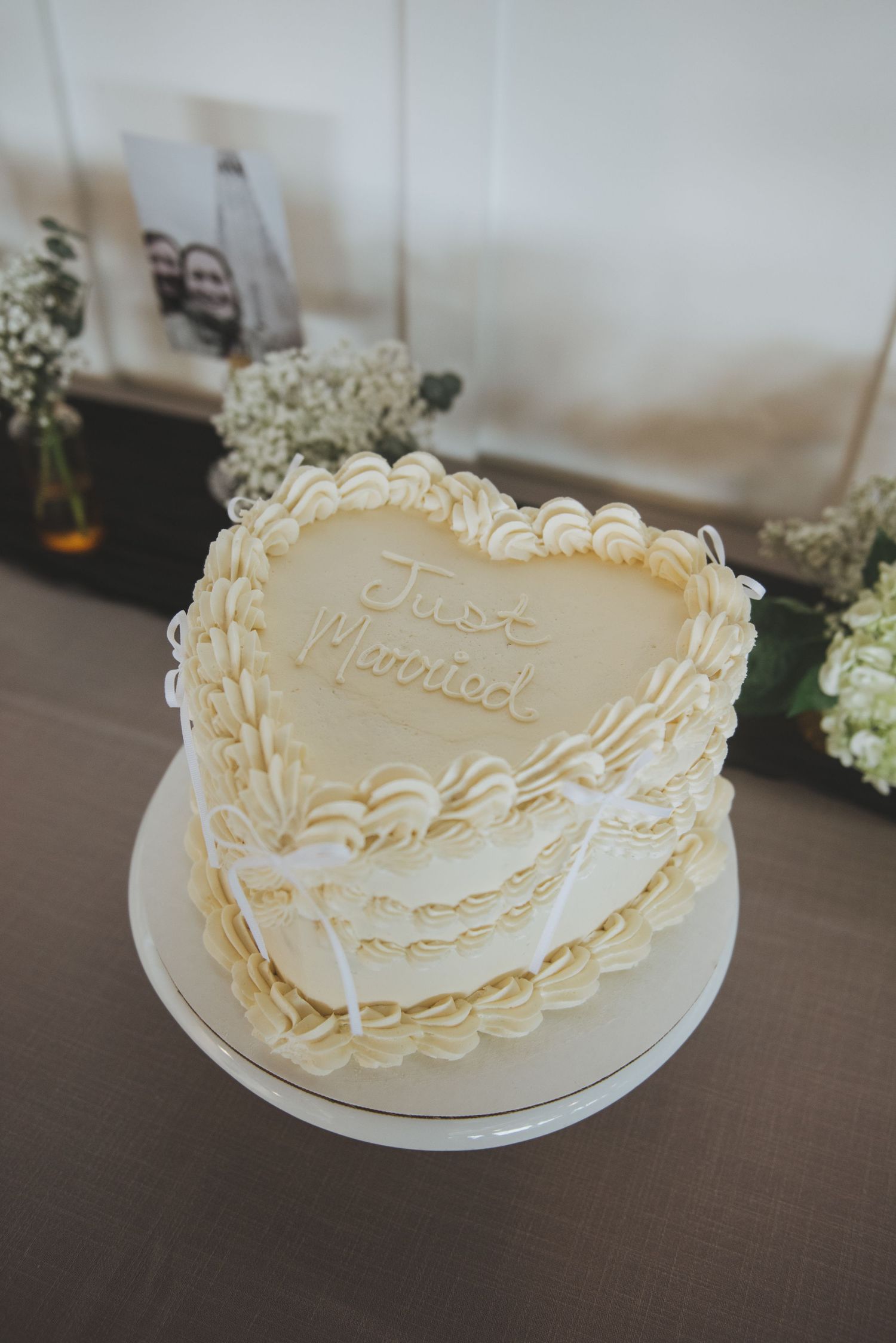 Elegant heart-shaped wedding cake with intricate white piping details.