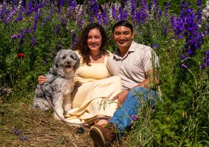 A couple sits together in a field of vibrant purple wildflowers on a sunny afternoon. Engagement session Richardson, Texas