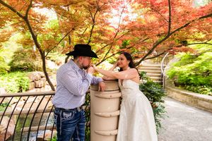 A couple sharing a romantic moment by a stone pillar in Dallas Arboretum. Engagement session. Couples session