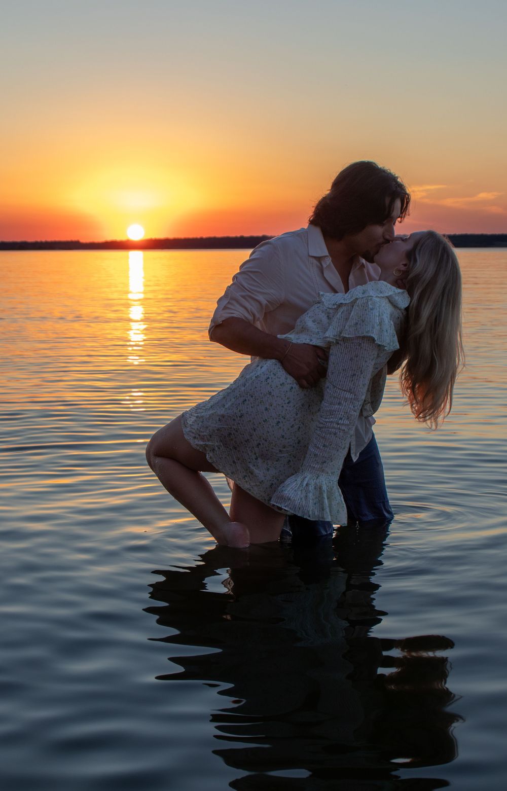 Silhouetted couple sharing a romantic moment in water during sunset. Engagement session. Sunset couples photos. Summer sunset couples