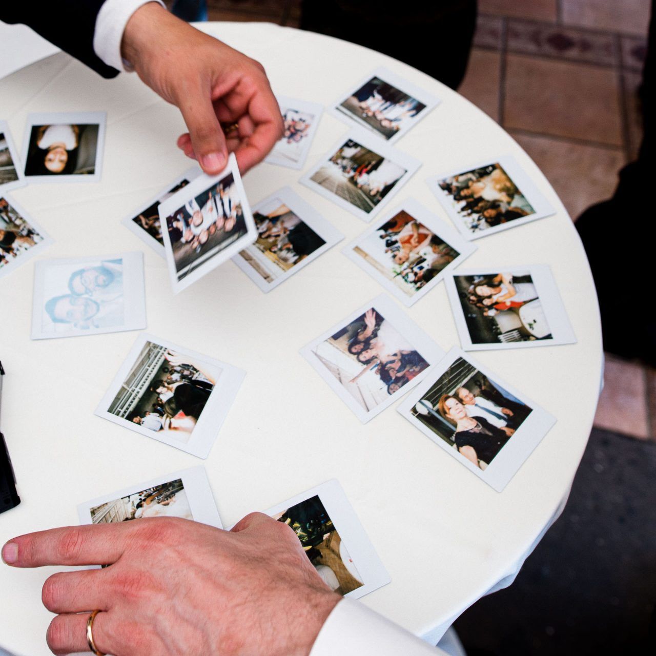 Polaroid photographs spread out on white round table.