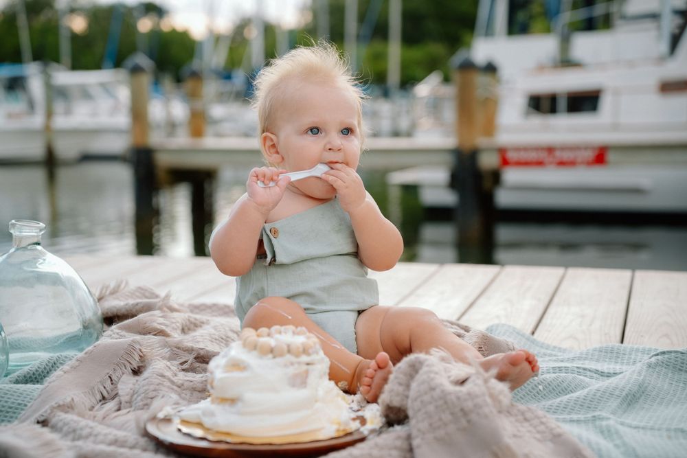 One year old eating smash cake on pier