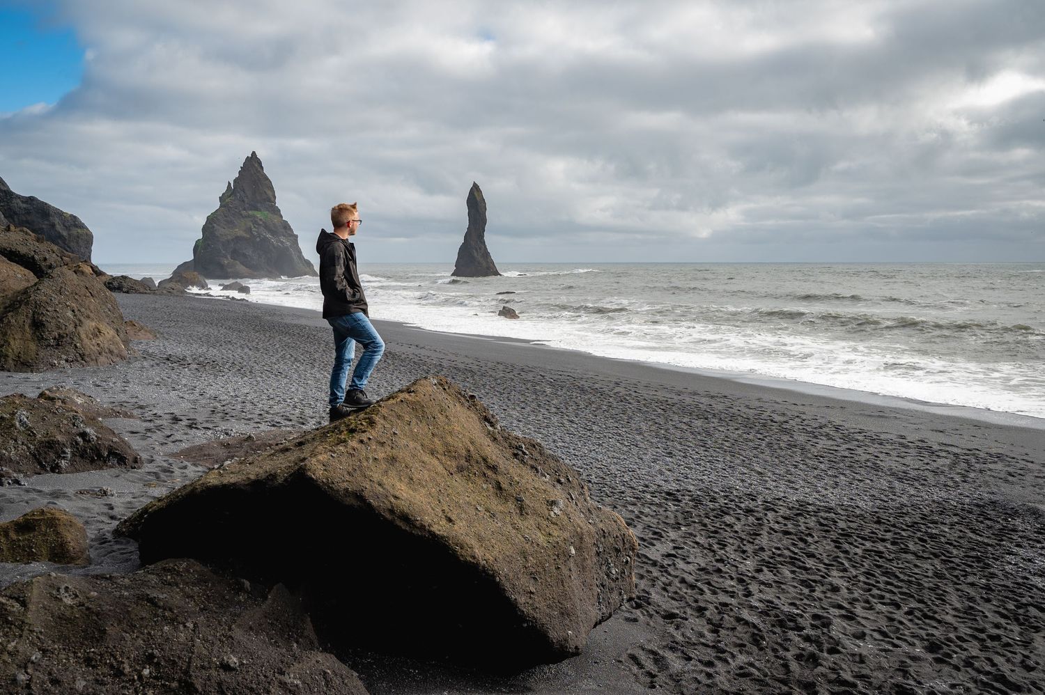 Dramatic black beach landscape with towering rock formations and rough ocean waves in Iceland.