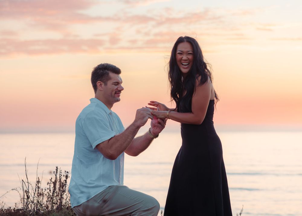 Surprise proposal moment at sunset by the ocean with joyful reaction.