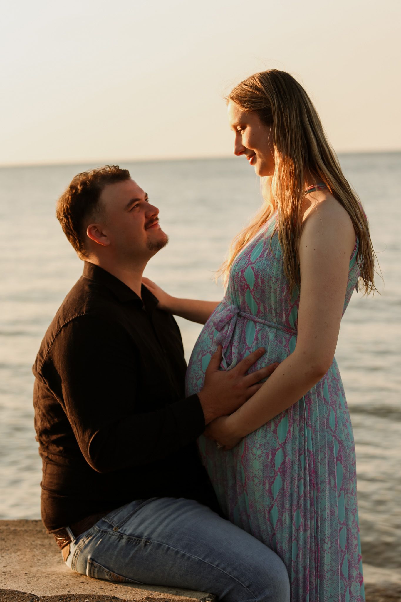 Couple shares intimate moment at sunset by the ocean.