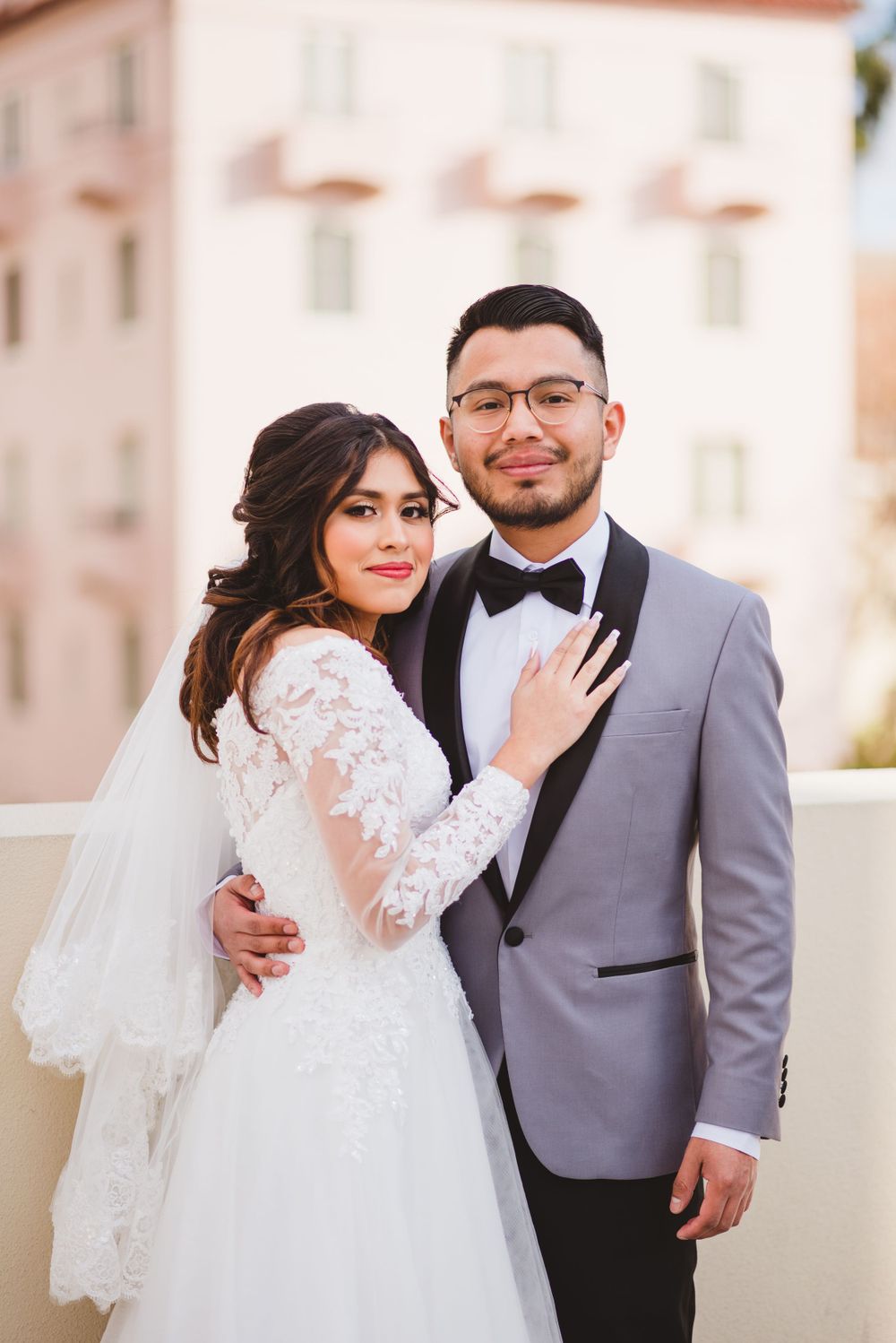 A newlywed couple poses in front of Pasadena City Hall, the architecture providing a backdrop for their wedding photos.
