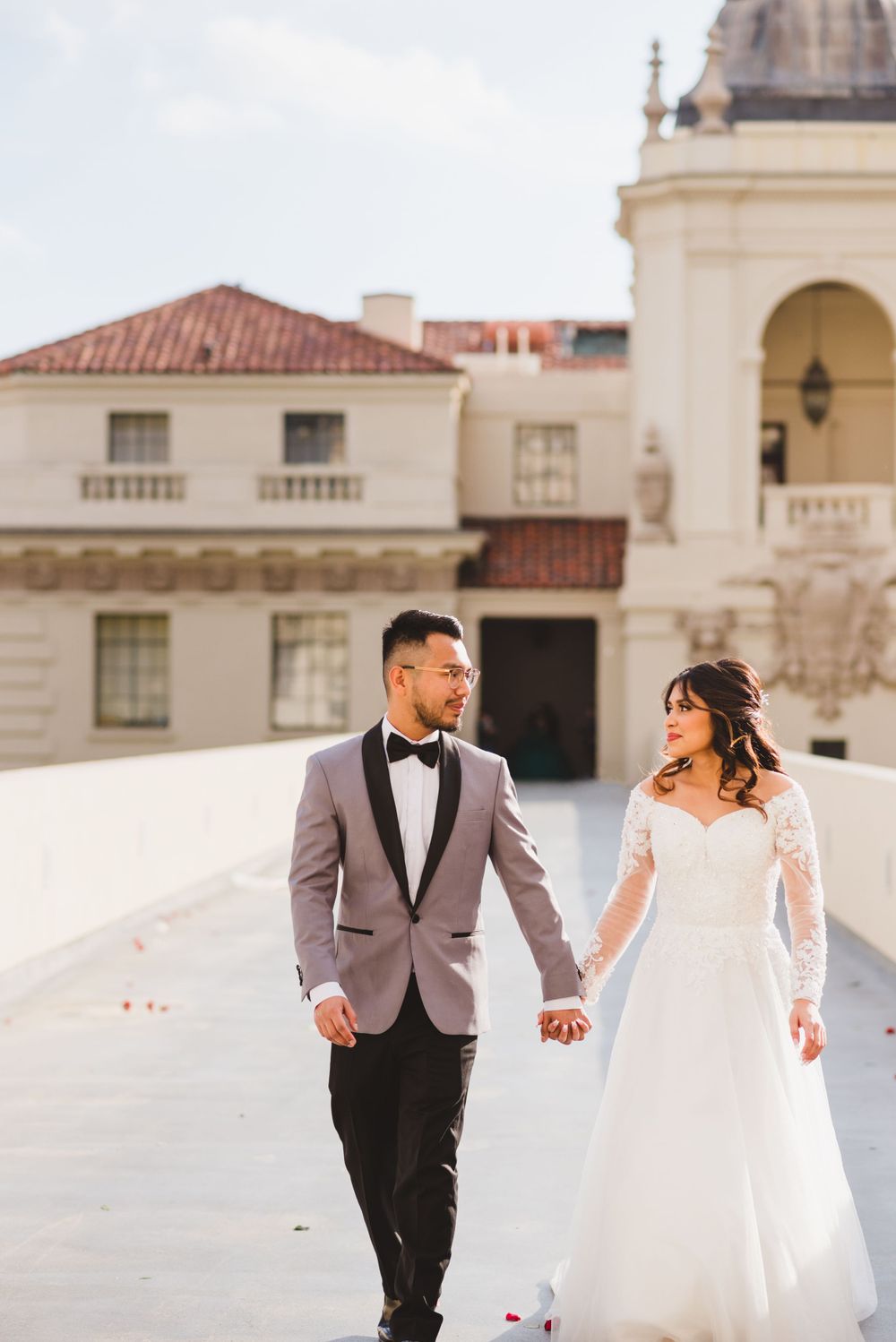 A newlywed couple poses in front of Pasadena City Hall, the architecture providing a backdrop for their wedding photos.