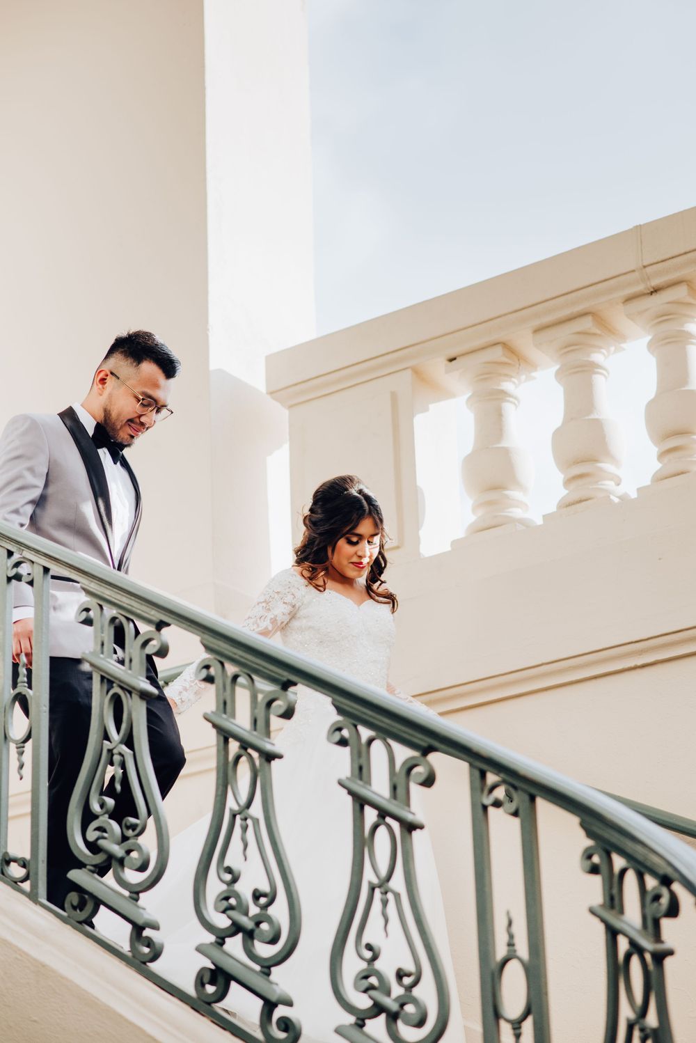 A newlywed couple poses in front of Pasadena City Hall, the architecture providing a backdrop for their wedding photos.