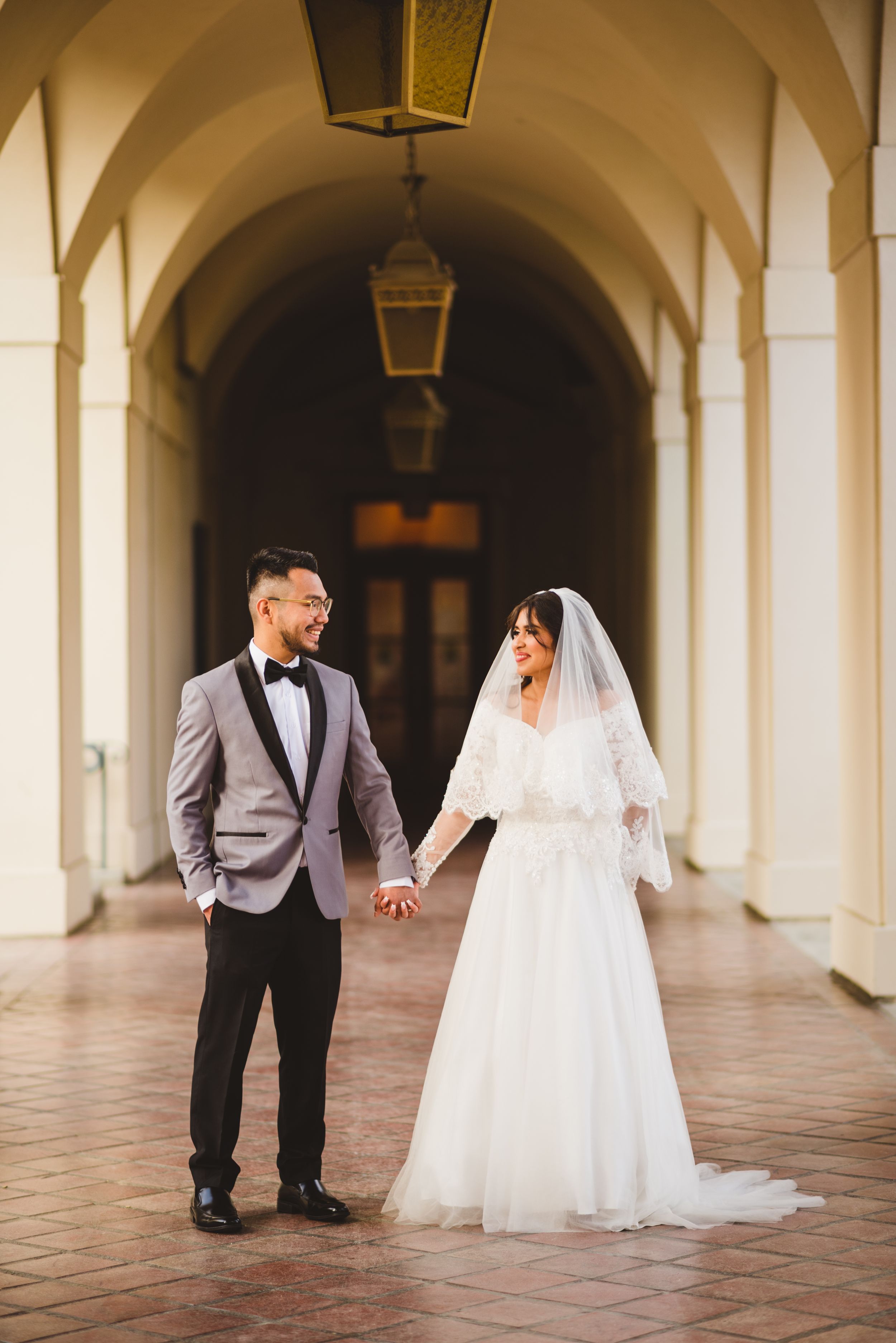 At Pasadena City Hall, the bride and groom walk hand in hand, their wedding photos reflecting their love.