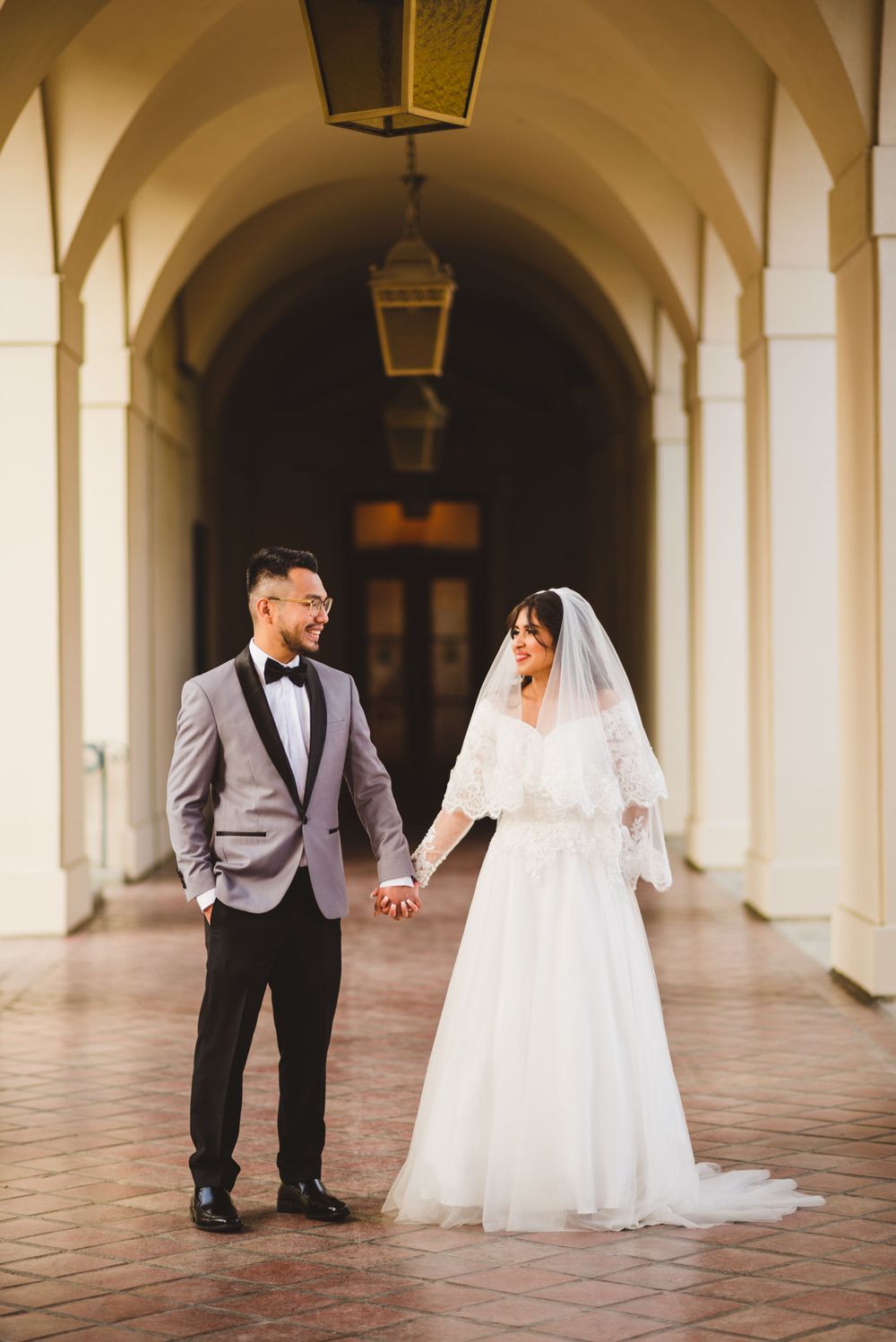 At Pasadena City Hall, the bride and groom walk hand in hand, their wedding photos reflecting their love.