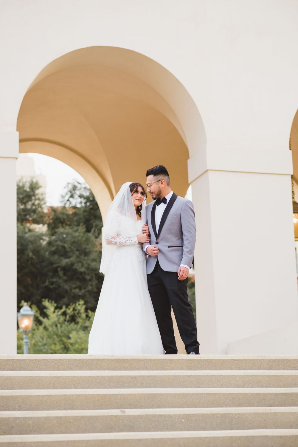 At Pasadena City Hall, the bride and groom walk hand in hand, their wedding photos reflecting their love.