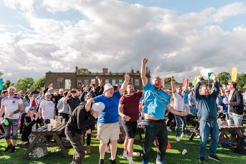 Large group of people dancing together outdoors on a sunny day with cloudy skies.
