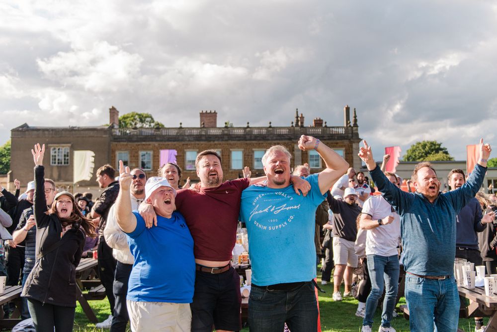 A group of people celebrating at an outdoor event with flags and banners waving in the air.
