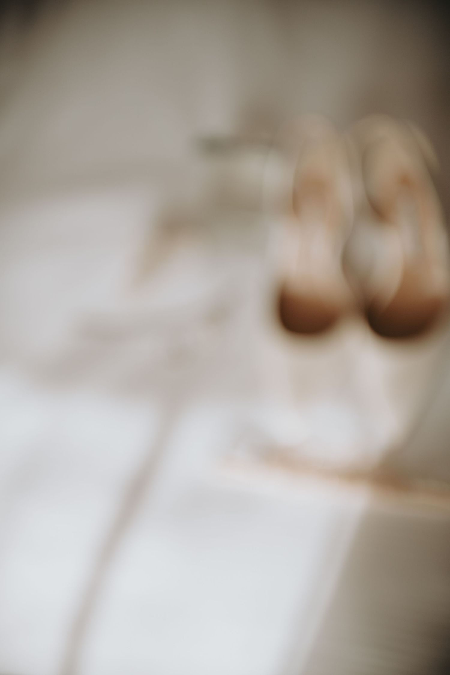 Soft focus image of nude wedding shoes arranged on a white surface.