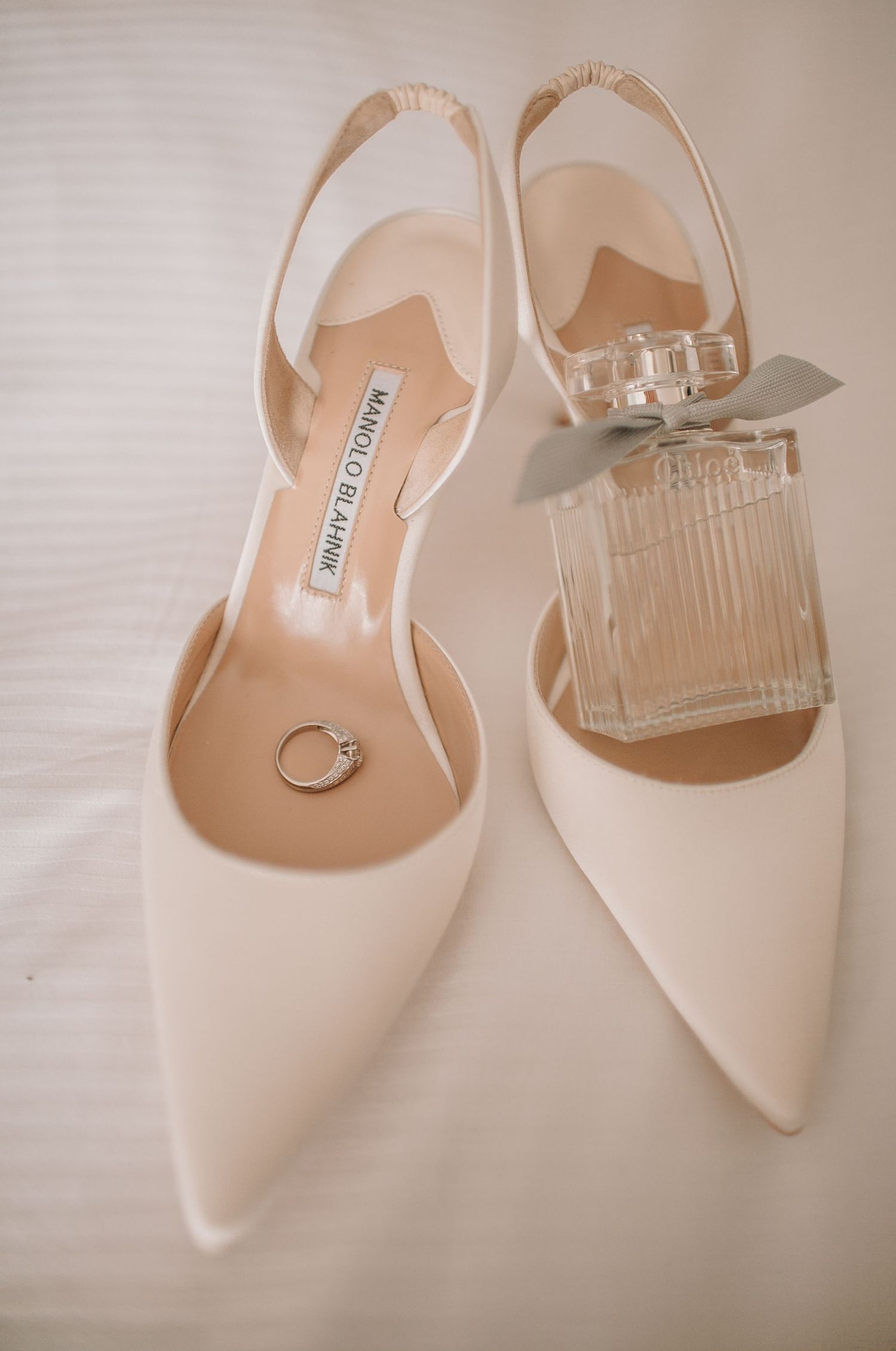 White pointed-toe wedding shoes with delicate ankle straps shown from multiple angles.