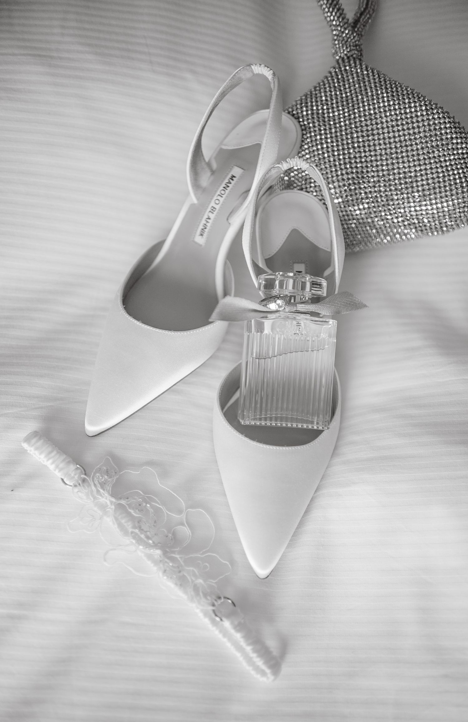Classic white wedding heels with crystal details captured in black and white photography.