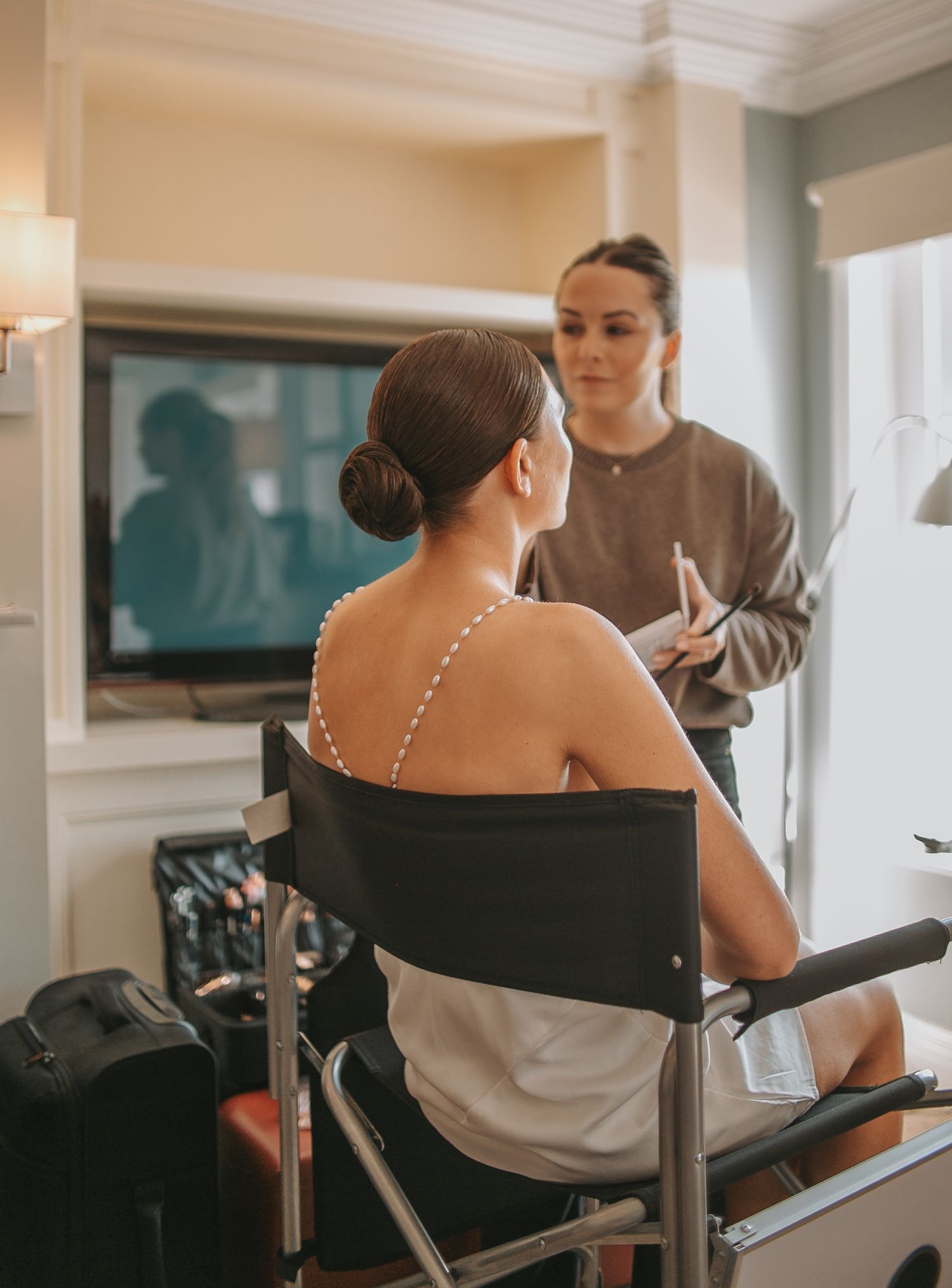 Wedding preparation scene with stylist working in a naturally lit room.