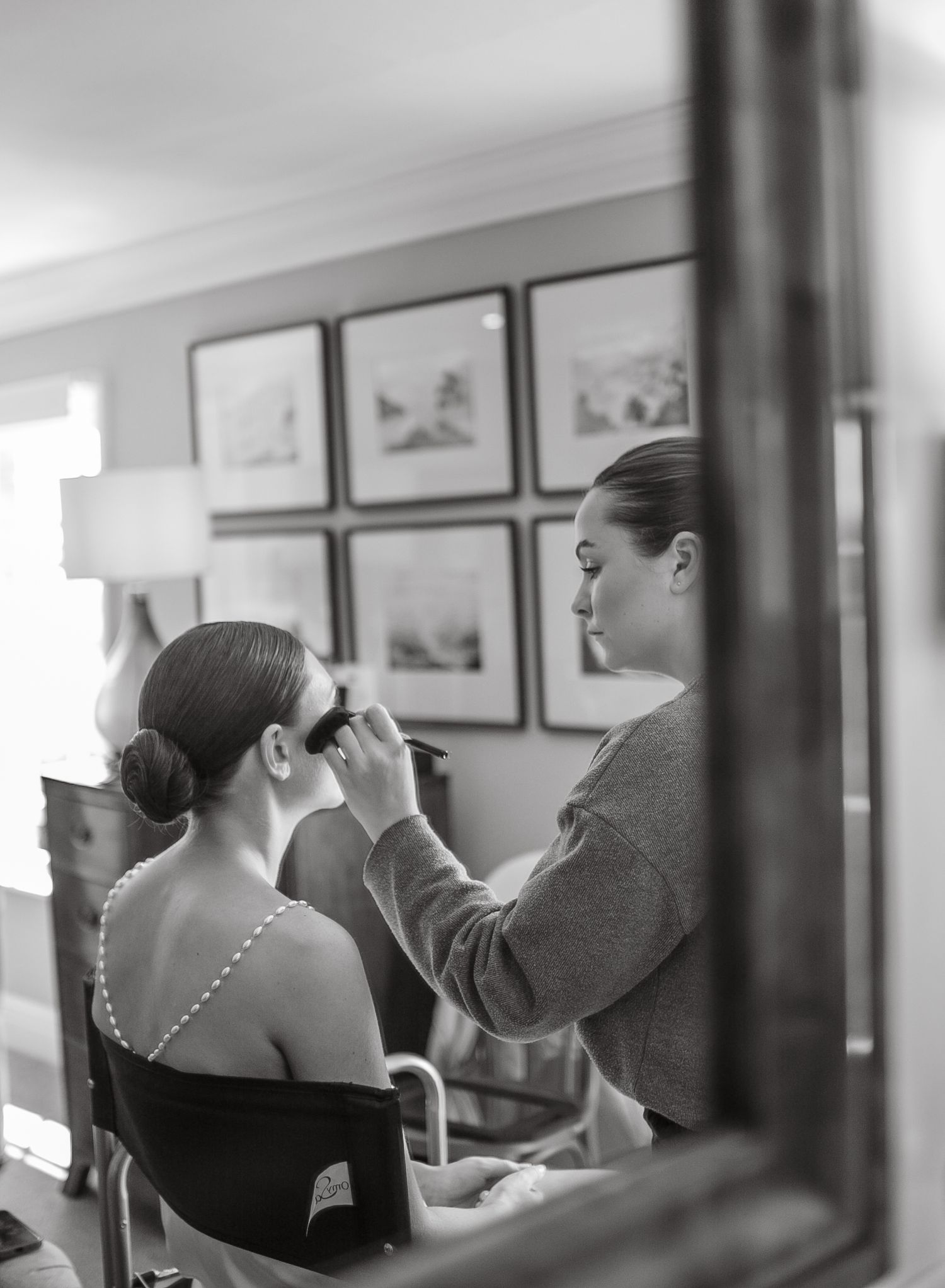 Black and white reflection of wedding preparation through mirror frame.
