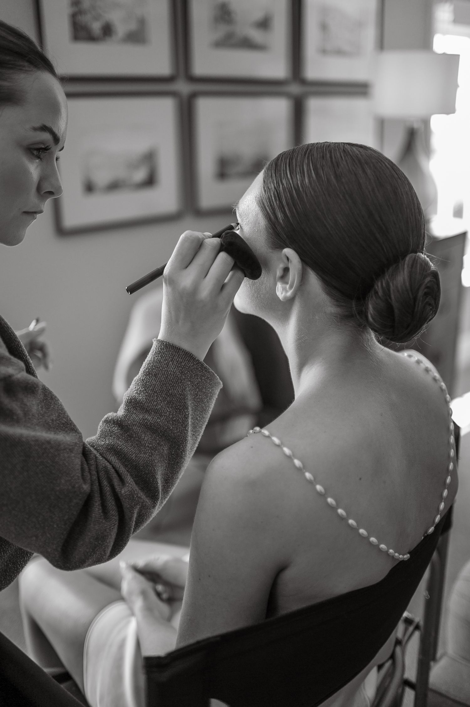 Makeup artist applies finishing touches to a bridal look in black and white.