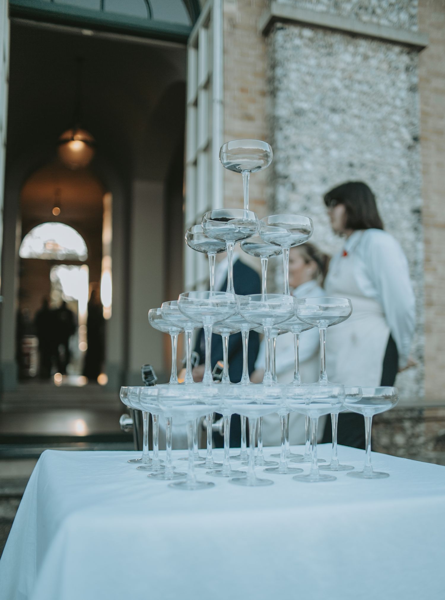 Empty champagne glasses arranged on white tablecloths at an elegant wedding reception.