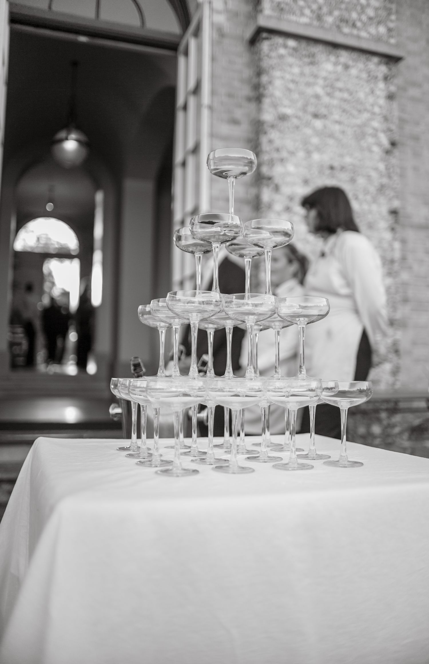 Black and white photo of champagne glasses set up on tables at a wedding venue.