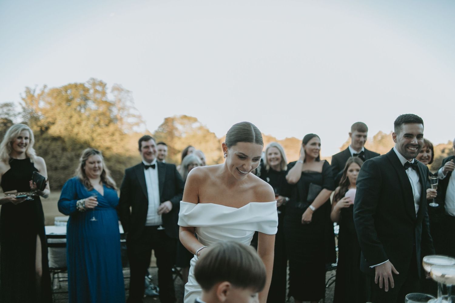 Guests watch as champagne cascades down crystal glasses at an elegant outdoor celebration.